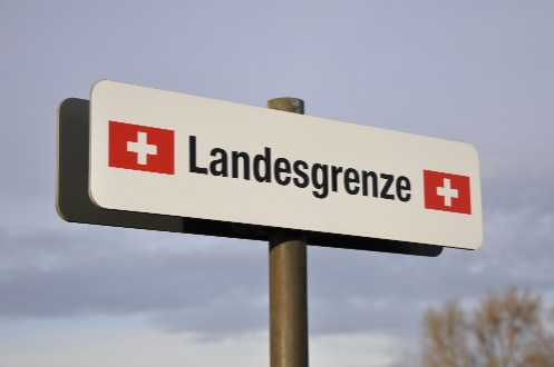 Schild mit der Aufschrift Landesgrenze und zwei Schweizerkreuzen links und rechts.